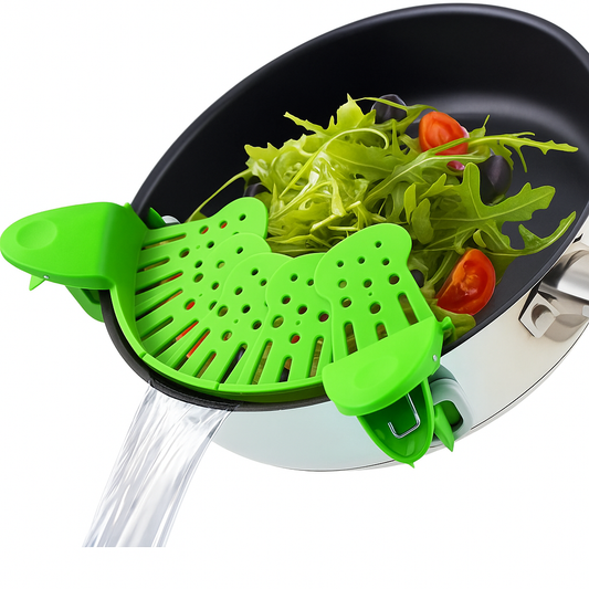 Green silicone clip-on strainer draining water from pan with fresh vegetables and cherry tomatoes