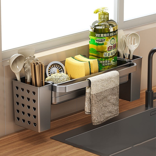 Wall-mounted multi-purpose kitchen rag rack with heart-shaped utensil holder, holding sponges, brushes, soap bottle, and towel above a sink.