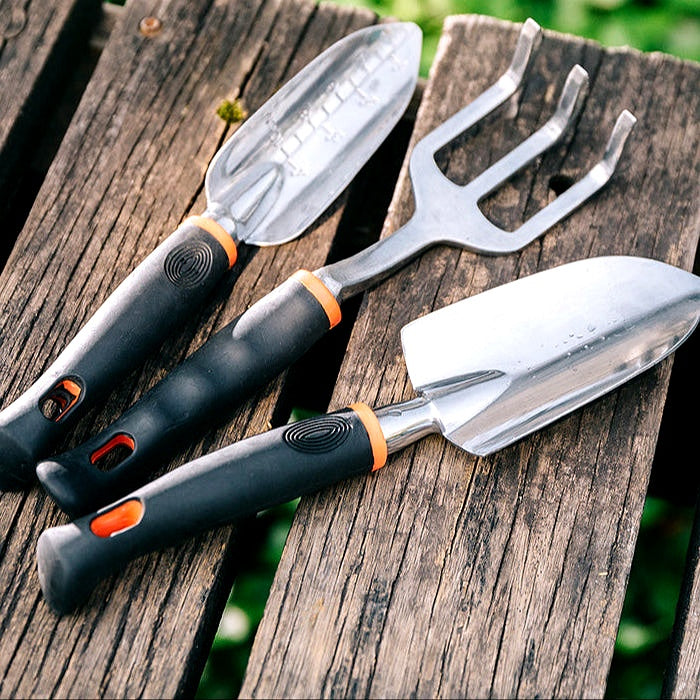 Garden hand tools set displayed on a rustic wooden table outdoors