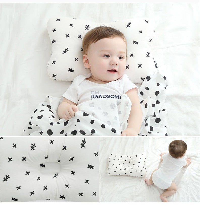 Baby lying on a white blanket with black patterns, wearing a 'HANDSOME' onesie.