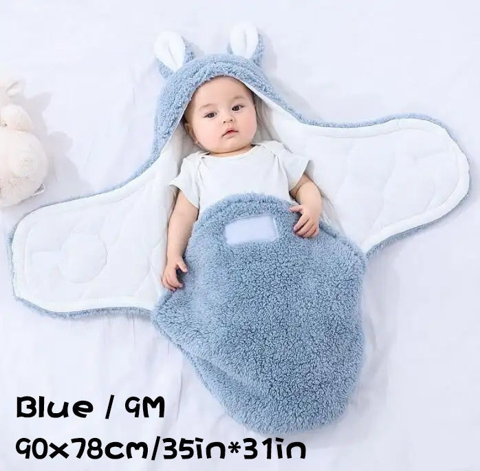 Baby in a fluffy blue swaddle sleeping bag with size dimensions displayed (90×78cm / 35in×31in).