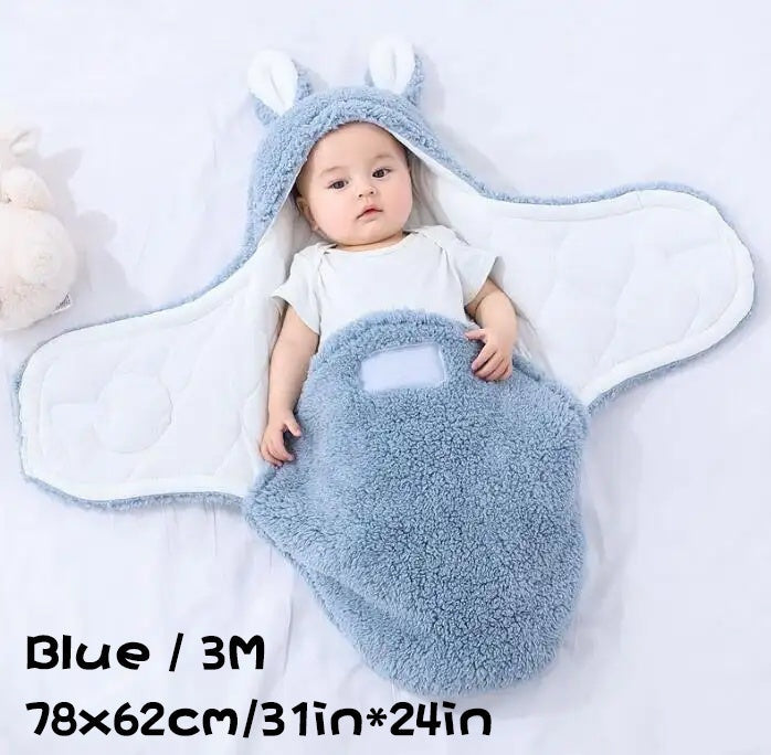 Blue fluffy baby swaddle sleeping bag with dimensions shown, featuring a baby in a bunny-eared hooded wrap