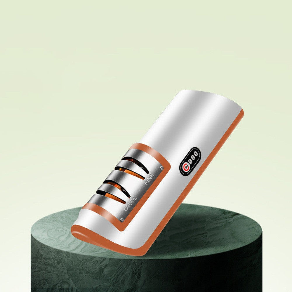 Orange variant of the electric knife and scissor sharpener displayed on a minimalist green platform with dual sharpening slots.
