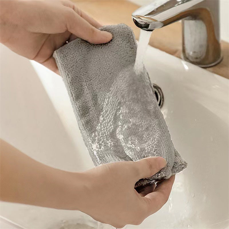 Hands washing removable microfiber mop pad under running water in sink