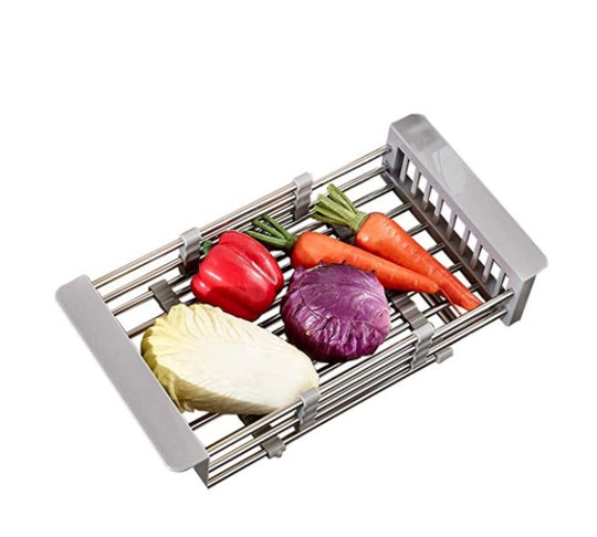 Gray expandable stainless steel sink basket filled with assorted vegetables, ideal for washing and draining produce.