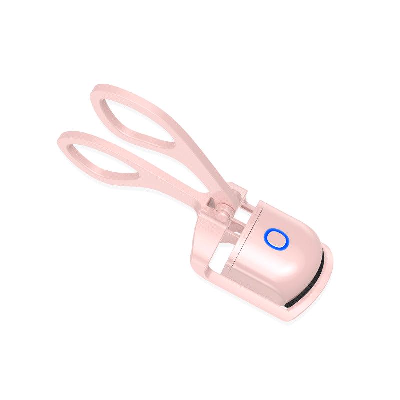 Pink heated eyelash curler with blue LED button on white background