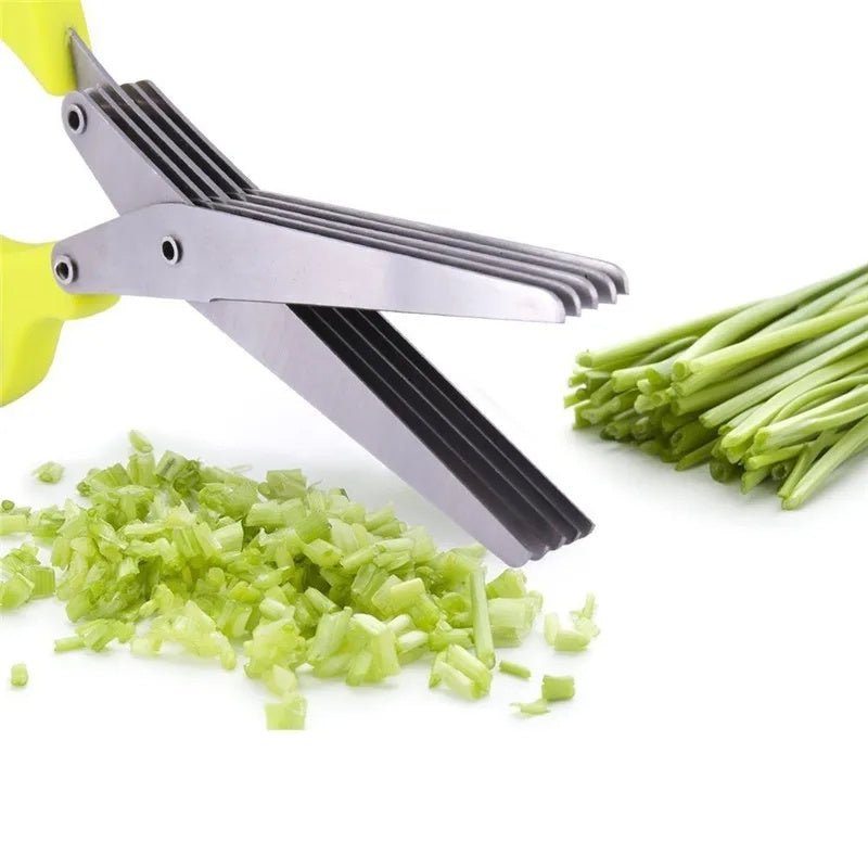 Green-handled herb scissors cutting chives with chopped greens on white surface