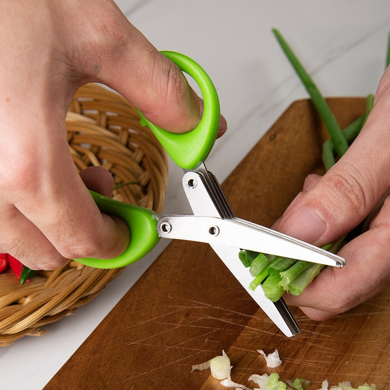 Multi-layer herb scissors with green handle cutting green onions on wooden board