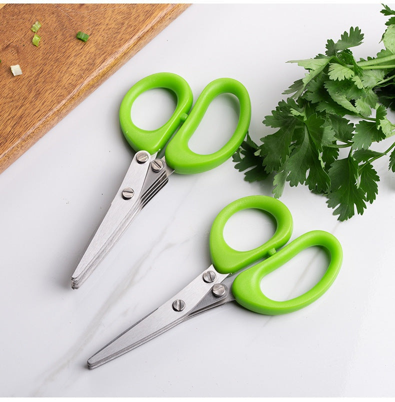 Two herb scissors with green handles on a kitchen counter with parsley