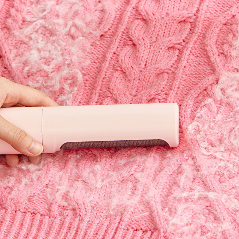 Reusable pet hair remover brush cleaning lint and fur from a pink knitted sweater