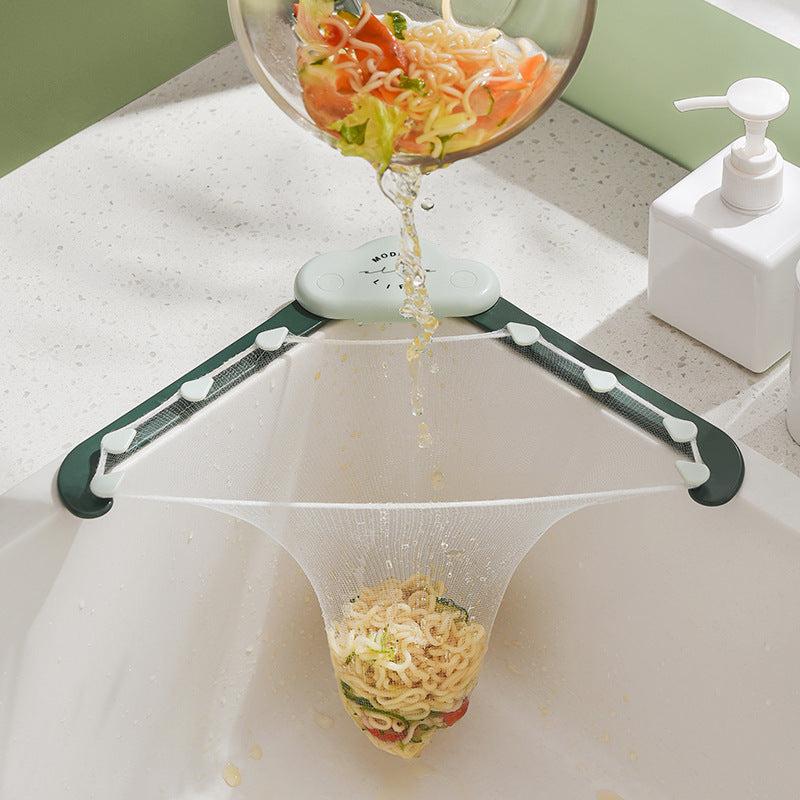 Triangular sink strainer in use, capturing food waste like noodles and vegetables from a bowl being poured into the sink