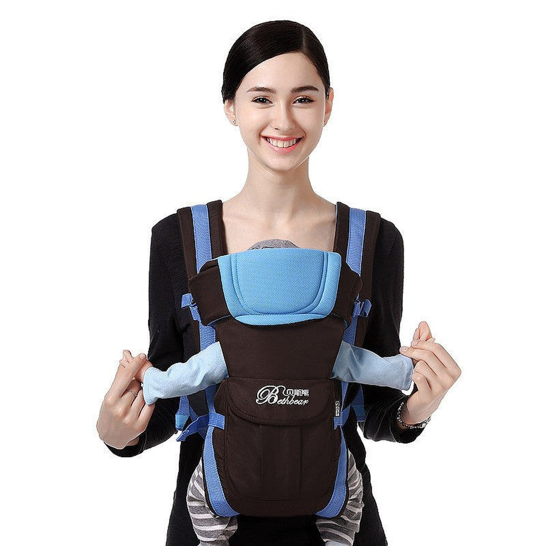 Smiling mother wearing a blue and black baby carrier with a newborn in front-facing position, demonstrating all-season ergonomic use.