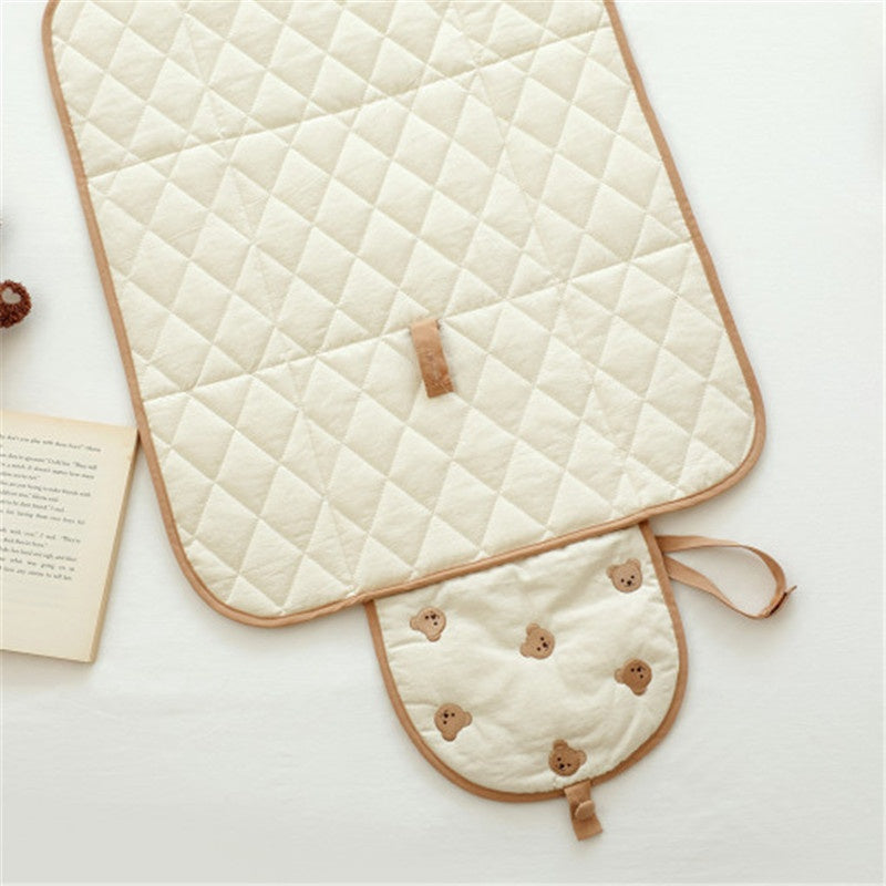 Foldable baby changing pad with bear pattern, open and ready for use during travel