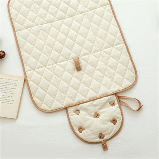 Foldable baby changing pad with bear pattern, open and ready for use during travel