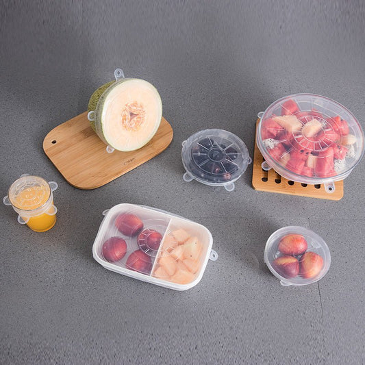 Reusable silicone lids covering various fruits and containers on kitchen counter