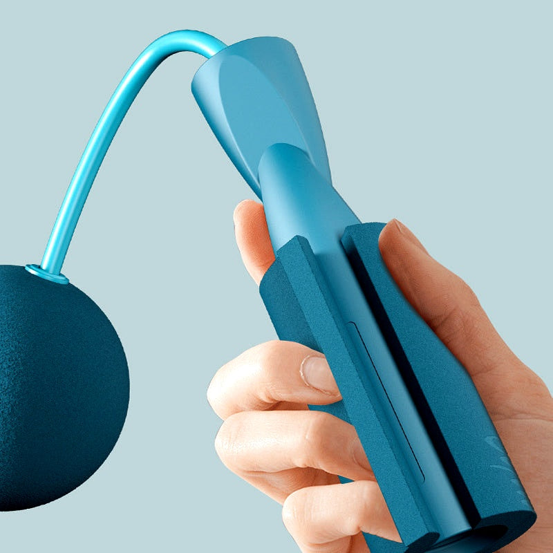 Close-up of a hand holding the foam handle of a cordless weighted jump rope with blue ball attachment.