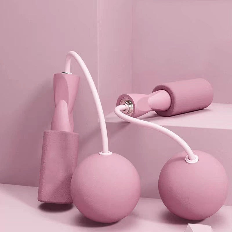 Pink cordless weighted jump rope set with foam handles and spherical weights, displayed on a pastel pink background.