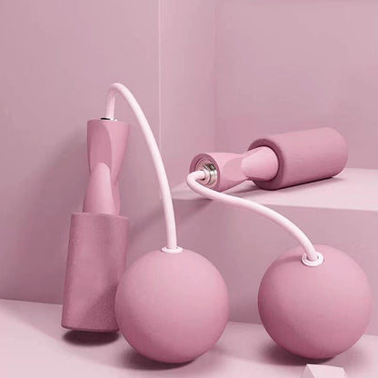 Pink cordless weighted jump rope set with foam handles and spherical weights, displayed on a pastel pink background.