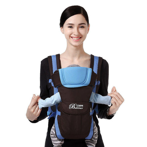 Mother wearing a baby in a blue and black carrier sling with padded support and adjustable straps.