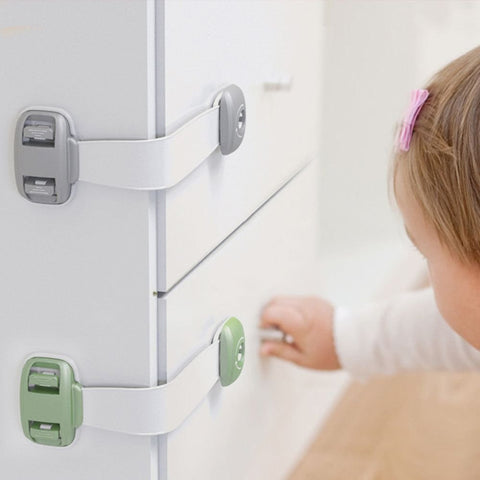 Child safety drawer straps in use preventing toddler from opening cabinet