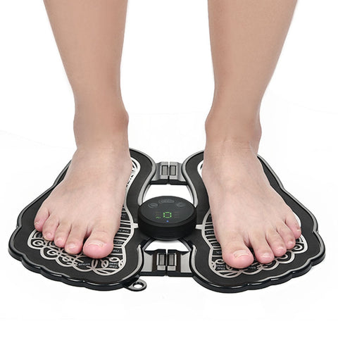 Person using a foldable electronic foot massager pad with digital display and reflexology zones.