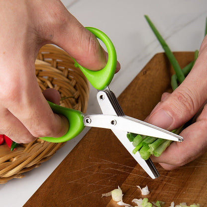 Multi-layer herb scissors with green handle cutting green onions on wooden board