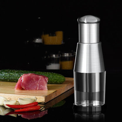 Stainless steel manual garlic and onion press placed on a kitchen counter with fresh ingredients.