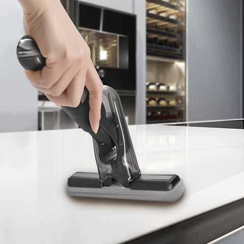 Hand using mini spray mop to clean a kitchen countertop