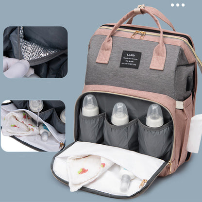 Open view of mummy baby backpack showing insulated bottle pockets and wet-dry compartment