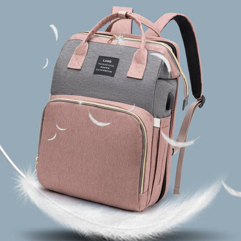 Pink and gray mummy baby crib backpack with feather-light design on a blue background