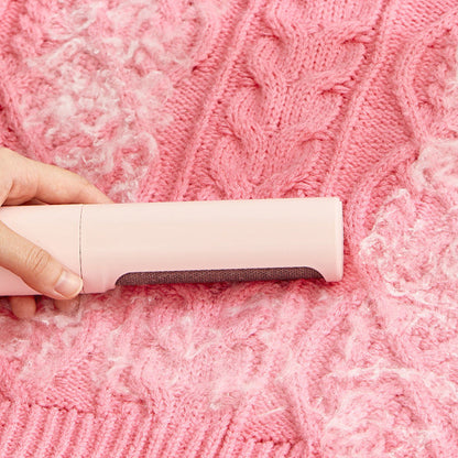 Reusable pet hair remover brush cleaning lint and fur from a pink knitted sweater