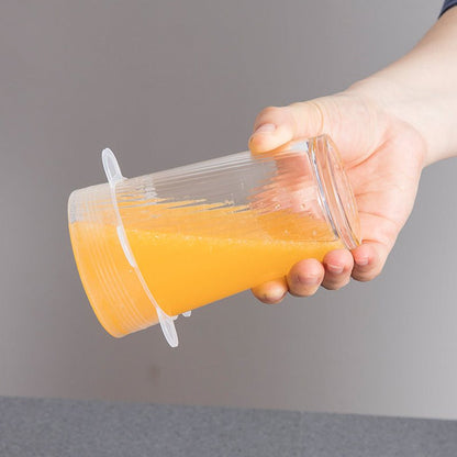 Glass of orange juice turned sideways with silicone lid securely preventing leaks