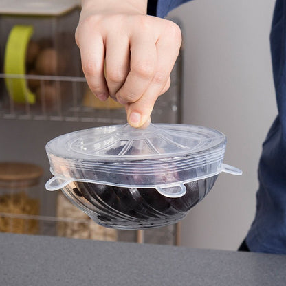 Hand lifting a bowl by its silicone lid to show strong airtight grip