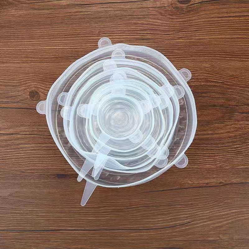 Top view of stacked silicone food lids in multiple sizes on wooden surface