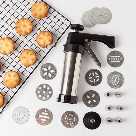 Stainless steel cookie press kit with 13 discs and 8 icing tips on a white background