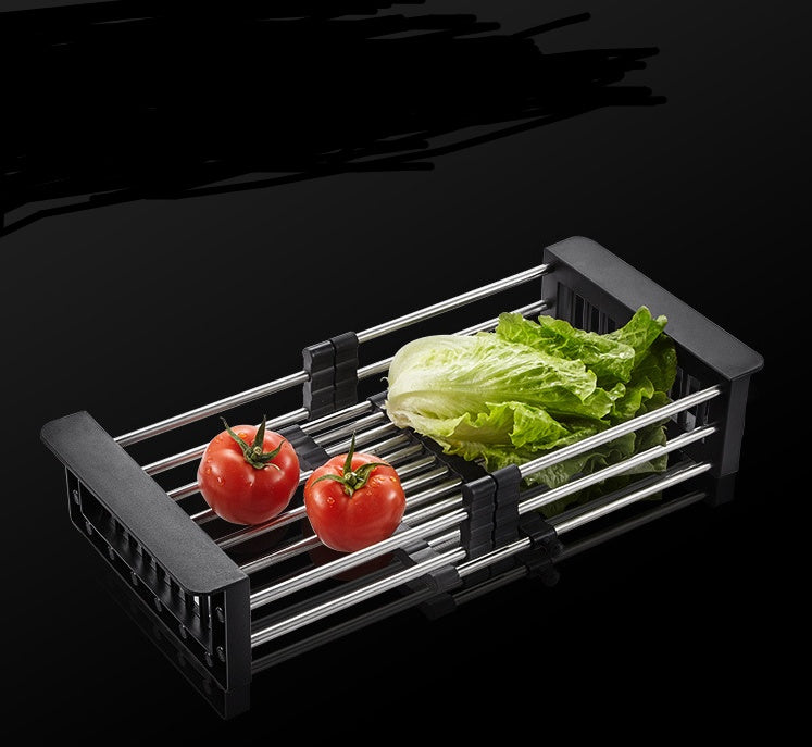 Black expandable stainless steel sink basket with lettuce and tomatoes, ideal for washing and draining vegetables.