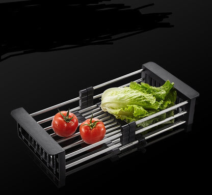Black expandable stainless steel sink basket with lettuce and tomatoes, ideal for washing and draining vegetables.