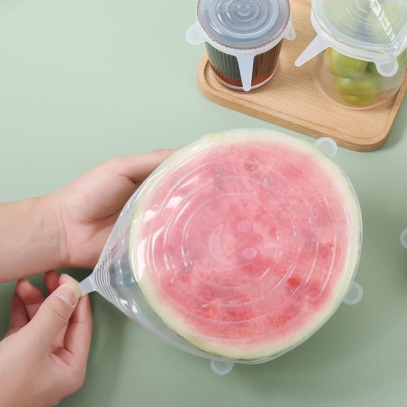 Hands stretching a silicone lid over a halved watermelon for food storage