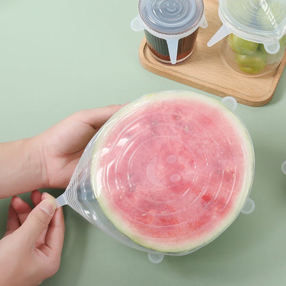 Hands stretching a silicone lid over a halved watermelon for food storage
