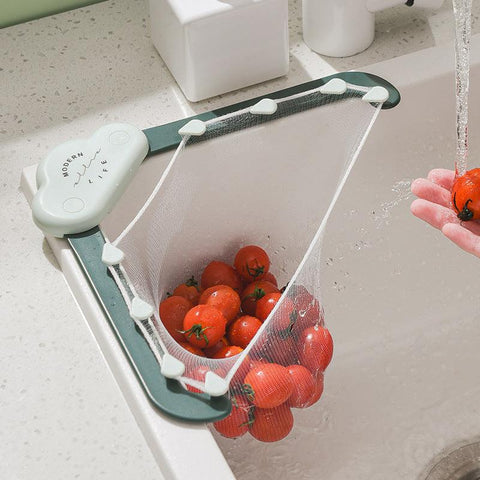 Triangular sink filter holder installed in a kitchen sink, filled with cherry tomatoes being rinsed under running water