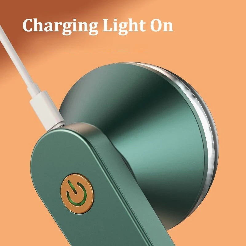 Close-up of a green USB electric lint remover showing charging light and USB cable connection.