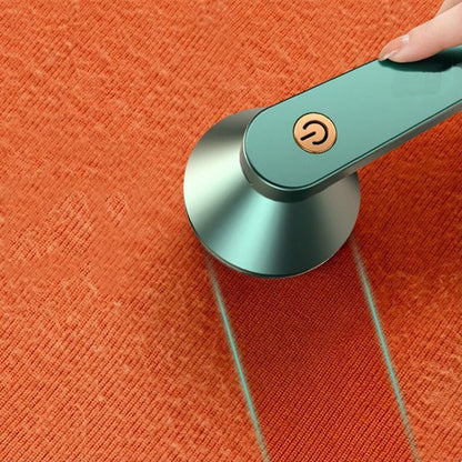 Green USB electric lint remover shown in action on an orange fabric, highlighting the cleaned area.
