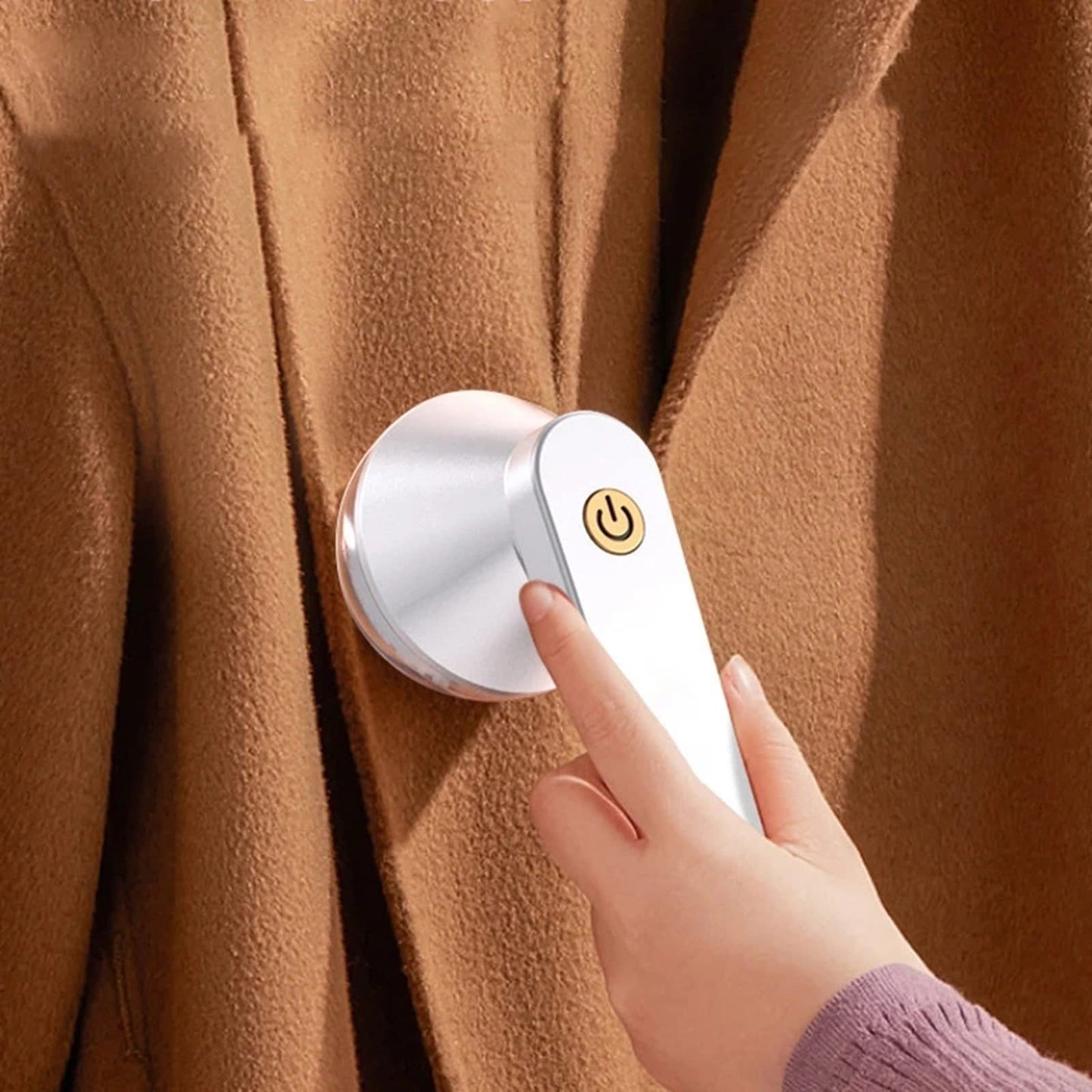 Person using a white USB electric lint remover on a brown wool coat.