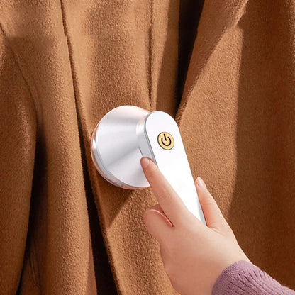 Person using a white USB electric lint remover on a brown wool coat.